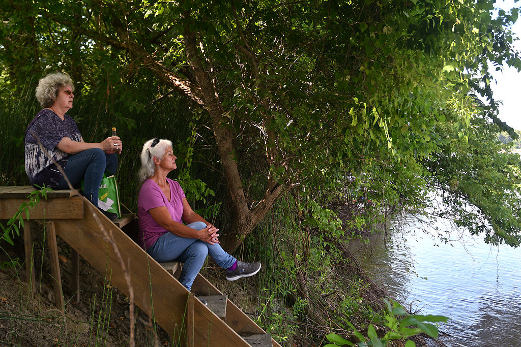 Debi Stokes, left, and Tonja Chamberlain, sit on a ladder leading down to the Missouri River